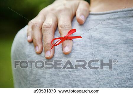 Stock Image - Red ribbon tied on index finger. Fotosearch