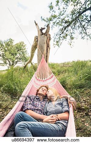 Stock Photo - Romantic teenage girl and boyfriend reclining in rural hammock. Fotosearch