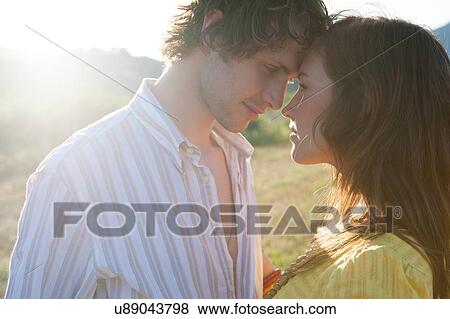Stock Photo - Romantic young couple face to face in field. Fotosearch