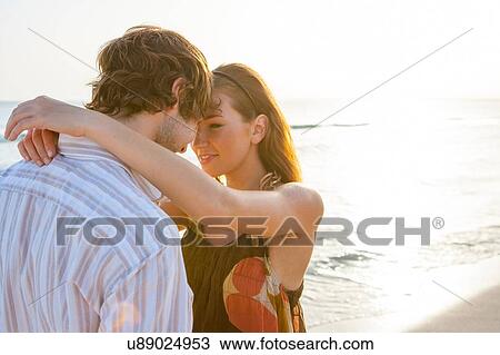 Stock Image - Romantic young couple face to face on sunlit beach, Majorca, Spain. Fotosearch
