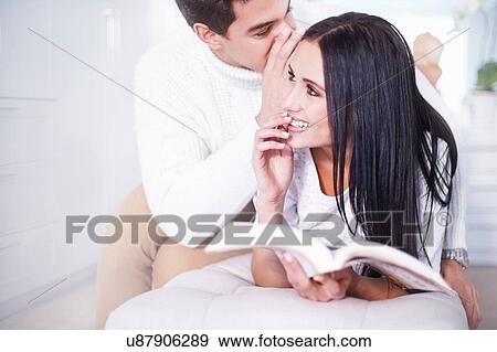 Romantic young man whispering to girlfriend in bedroom View Large Photo Image Stock Photo - Romantic young man whispering to girlfriend in bedroom. Fotosearch