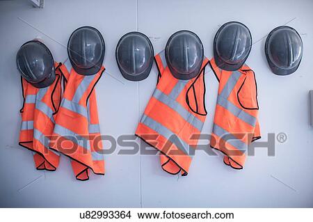 Rows of hard hats and high vis jackets on portable cabin wall View Large Photo Image Picture - Rows of hard hats and high vis jackets on portable cabin wall. Fotosearch