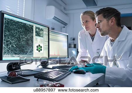 Stock Photo - Scientists with electron microscope studying metal structure. Fotosearch