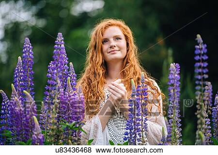 Serene young woman amongst purple wildflowers with hands clasped View Large Photo Image Stock Photo - Serene young woman amongst purple wildflowers with hands clasped. Fotosearch