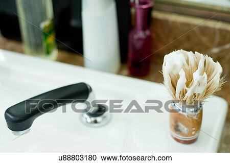 Stock Image - Shaving cream covered shaving brush on sink in barbershop. Fotosearch
