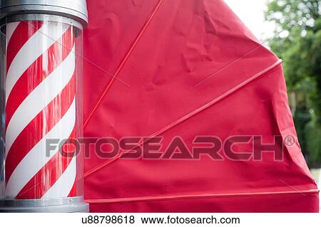 Stock Photo - Side view of barbers pole and red awning. Fotosearch