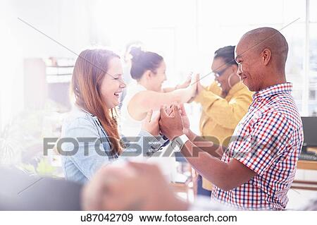 Side view of colleagues in team building task, face to face, hands together smiling View Large Photo Image Stock Photo - Side view of colleagues in team building task, face to face, hands together smiling. Fotosearch