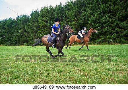 Side view of girl and mature woman wearing riding hats galloping on horseback View Large Photo Image Stock Photo - Side view of girl and mature woman wearing riding hats galloping on horseback. Fotosearch