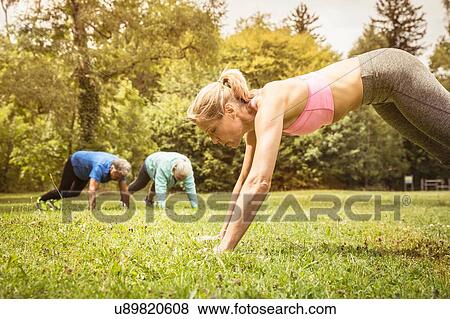 Side view of mature woman in park doing push ups on grass looking down View Large Photo Image Stock Photo - Side view of mature woman in park doing push ups on grass looking down. Fotosearch