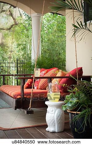 Stock Image - Side view of swing seat on porch. Fotosearch