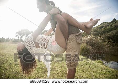 Side view of young man holding young woman, head back hanging on View Large Photo Image Stock Photo - Side view of young man holding young woman, head back hanging on. Fotosearch