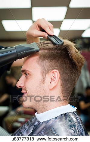 Side view of young man in barbershop having hair blow dried View Large Photo Image Stock Photo - Side view of young man in barbershop having hair blow dried. Fotosearch