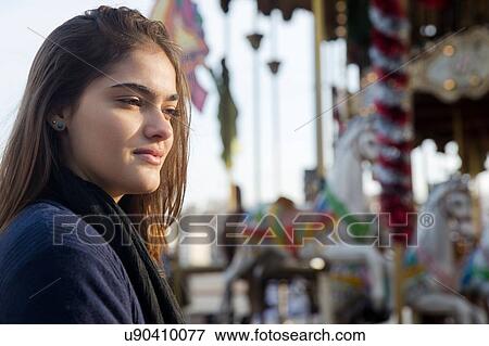 Side view of young woman, carousel in background View Large Photo Image Stock Photo - Side view of young woman, carousel in background. Fotosearch