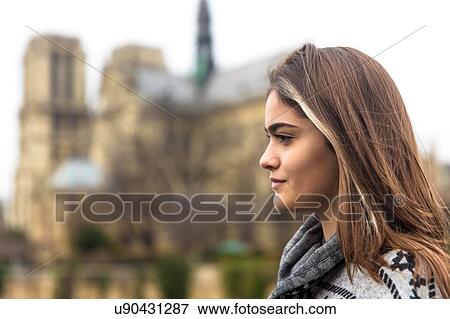 Side view of young woman, Notre Dame Cathedral in background, Paris, France View Large Photo Image Stock Photo - Side view of young woman, Notre Dame Cathedral in background, Paris, France. Fotosearch