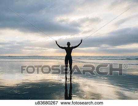Stock Photo - Silhouette of person raising arms on beach. Fotosearch