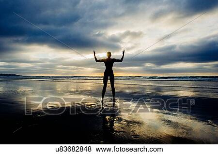 Stock Photo - Silhouette of person raising arms on beach. Fotosearch