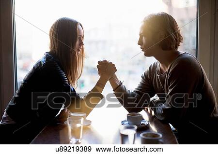 Silhouetted woman and young man holding hands over cafe table View Large Photo Image Stock Photo - Silhouetted woman and young man holding hands over cafe table. Fotosearch