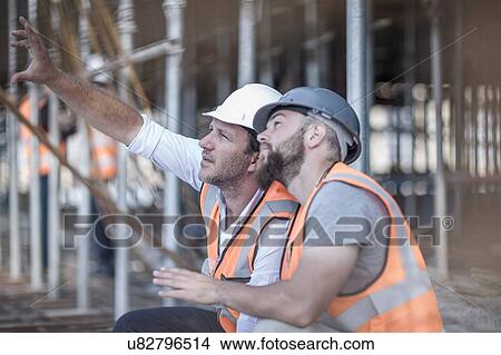 Picture - Site manager and builder looking up at steel rods on construction site. Fotosearch