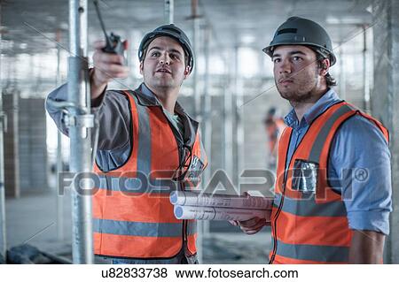 Stock Photo - Site manager and builder pointing on construction site. Fotosearch