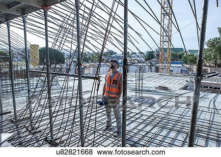 Stock Photo - Site manager looking up at steel rod structures on construction site. Fotosearch