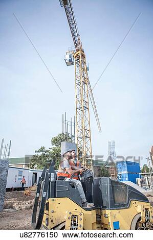 Stock Image - Site manager talking to steamroller driver on construction site. Fotosearch
