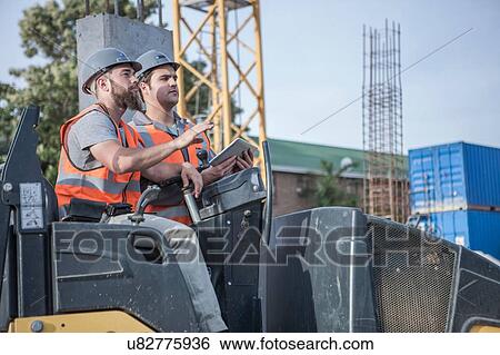 Stock Photograph - Site manager talking with steamroller driver on construction site. Fotosearch