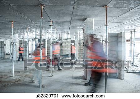 Stock Image - Six blurred construction workers on the go in busy construction site. Fotosearch