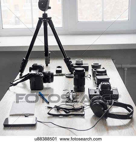 Stock Image - Smartphone and photography equipment on studio desk. Fotosearch