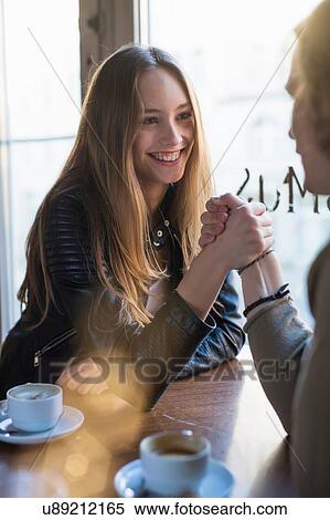 Smiling woman and young man holding hands over cafe table View Large Photo Image Stock Photography - Smiling woman and young man holding hands over cafe table. Fotosearch