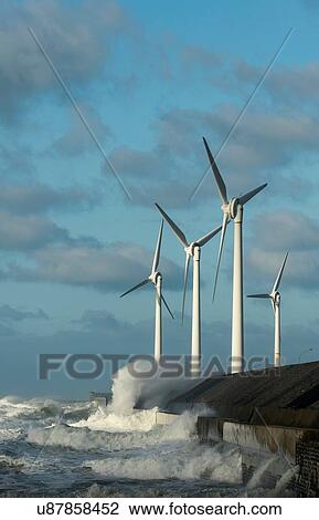 Stock Image - Stormy ocean waves splashing wind turbines and harbour wall, Boulogne-sur-Mer, Pas de Calais, France. Fotosearch
