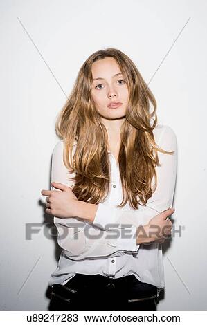 Stock Image - Studio portrait of confident mid adult woman with arms folded against white background. Fotosearch
