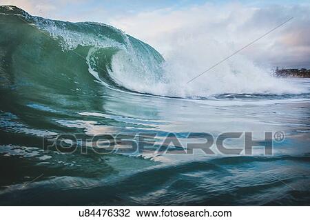 Stock Image - "Surface level view of blue ocean wave rolling and splashing near coast, Encinitas, California, USA". Fotosearch