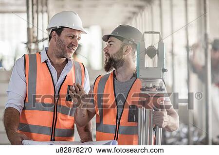 Stock Image - Surveyor explaining to site foreman on construction site. Fotosearch
