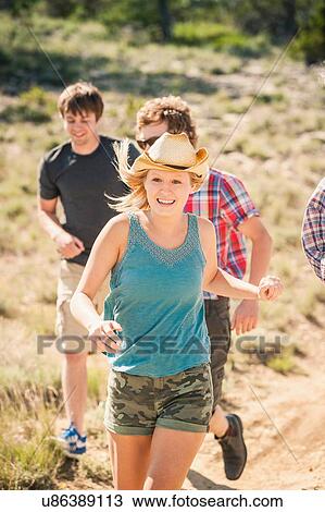 Stock Image - Teenage girl and adult friends running along dirt track, Bridger, Montana, USA. Fotosearch