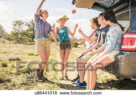 Stock Photograph - Teenage girl and adult friends sitting on car boot, Bridger, Montana, USA. Fotosearch