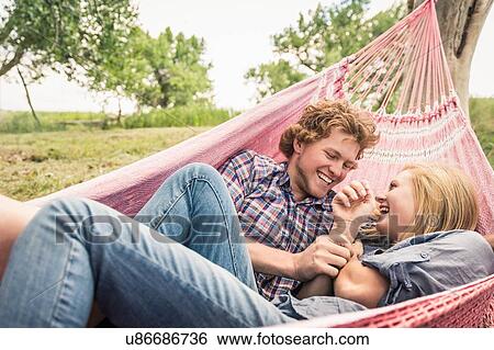 Stock Photograph - Teenage girl and boyfriend laughing in hammock. Fotosearch