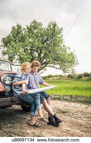 Teenage girl and boyfriend reading map on jeep bumper View Large Photo Image Picture - Teenage girl and boyfriend reading map on jeep bumper. Fotosearch