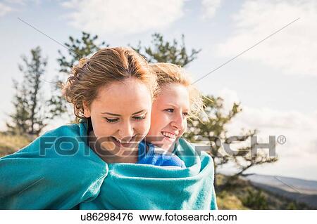 Stock Photograph - Teenage girl and friend wrapped in turquoise blanket, Bridger, Montana, USA. Fotosearch