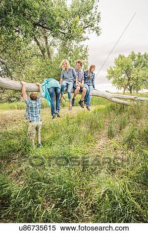 Teenage girl and young adult friends climbing and sitting on fallen tree View Large Photo Image Stock Photography - Teenage girl and young adult friends climbing and sitting on fallen tree. Fotosearch
