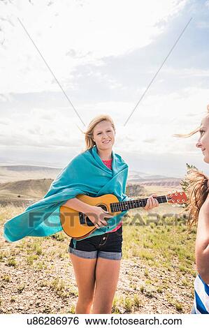 Teenage girl wrapped in blanket playing ukulele in hills, Bridger, Montana, USA View Large Photo Image Stock Photograph - Teenage girl wrapped in blanket playing ukulele in hills, Bridger, Montana, USA. Fotosearch