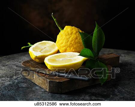 Textured lemon whole and halved with leaves on wooden chopping board with vintage knife View Large Photo Image Stock Photograph - Textured lemon whole and halved with leaves on wooden chopping board with vintage knife. Fotosearch