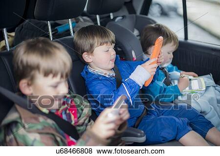 Stock Photo - Three brothers in car with digital device. Fotosearch