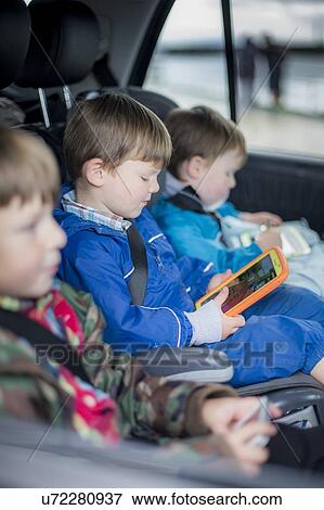 Three brothers in car with digital device View Large Photo Image Stock Photo - Three brothers in car with digital device. Fotosearch