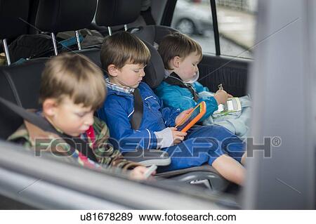 Stock Photo - Three brothers in car with digital device. Fotosearch