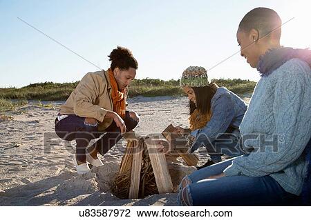 "Three friends on beach, preparing camp fire" View Large Photo Image Stock Image - "Three friends on beach, preparing camp fire". Fotosearch