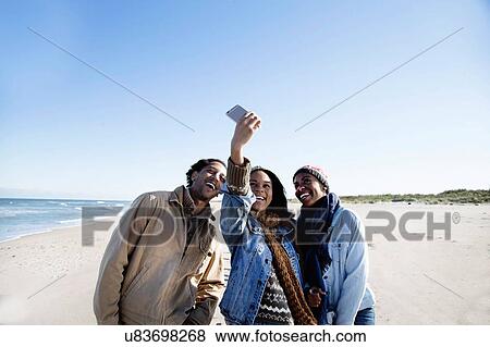 "Three friends on beach, taking self portrait, using smartphone" View Large Photo Image Stock Photo - "Three friends on beach, taking self portrait, using smartphone". Fotosearch