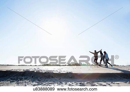 Stock Photo - Three friends walking along beach. Fotosearch