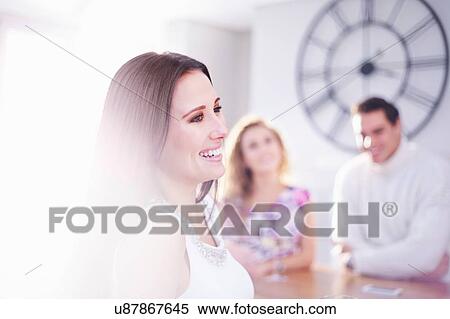 Stock Photography - Three happy young adult friends in kitchen. Fotosearch