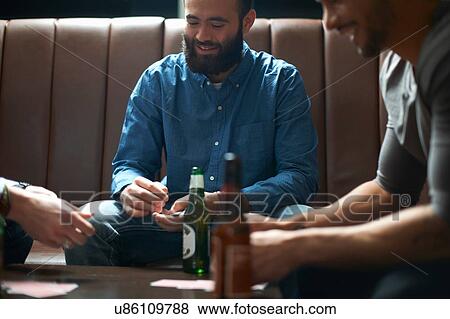Three male friends playing cards in traditional UK pub View Large Photo Image Stock Photo - Three male friends playing cards in traditional UK pub. Fotosearch