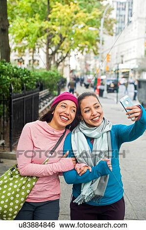 Twins walking and taking selfie with smartphone in park View Large Photo Image Stock Photograph - Twins walking and taking selfie with smartphone in park. Fotosearch